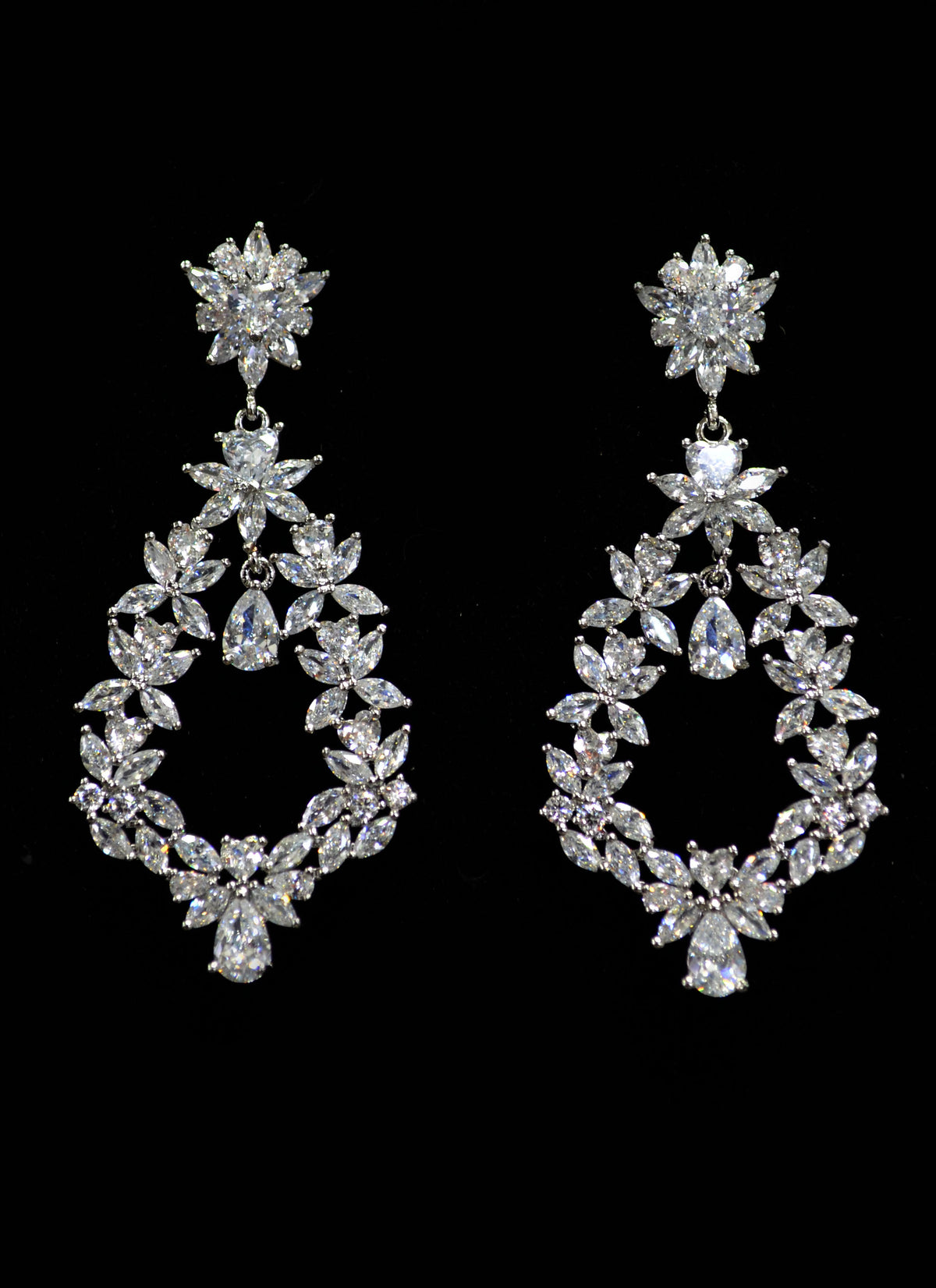 Oval crystal chandelier earrings featuring ornate open teardrop framed by round and marquise stones, product view at…