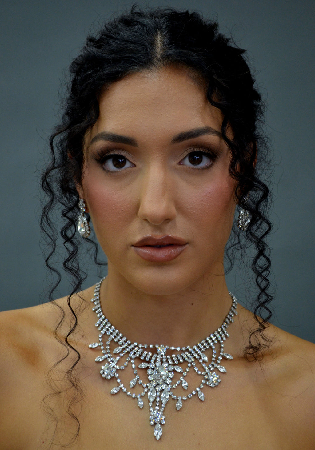 Statement crystal necklace-and-earring set featuring dramatic waterfall silhouette with marquise and teardrop stones,…
