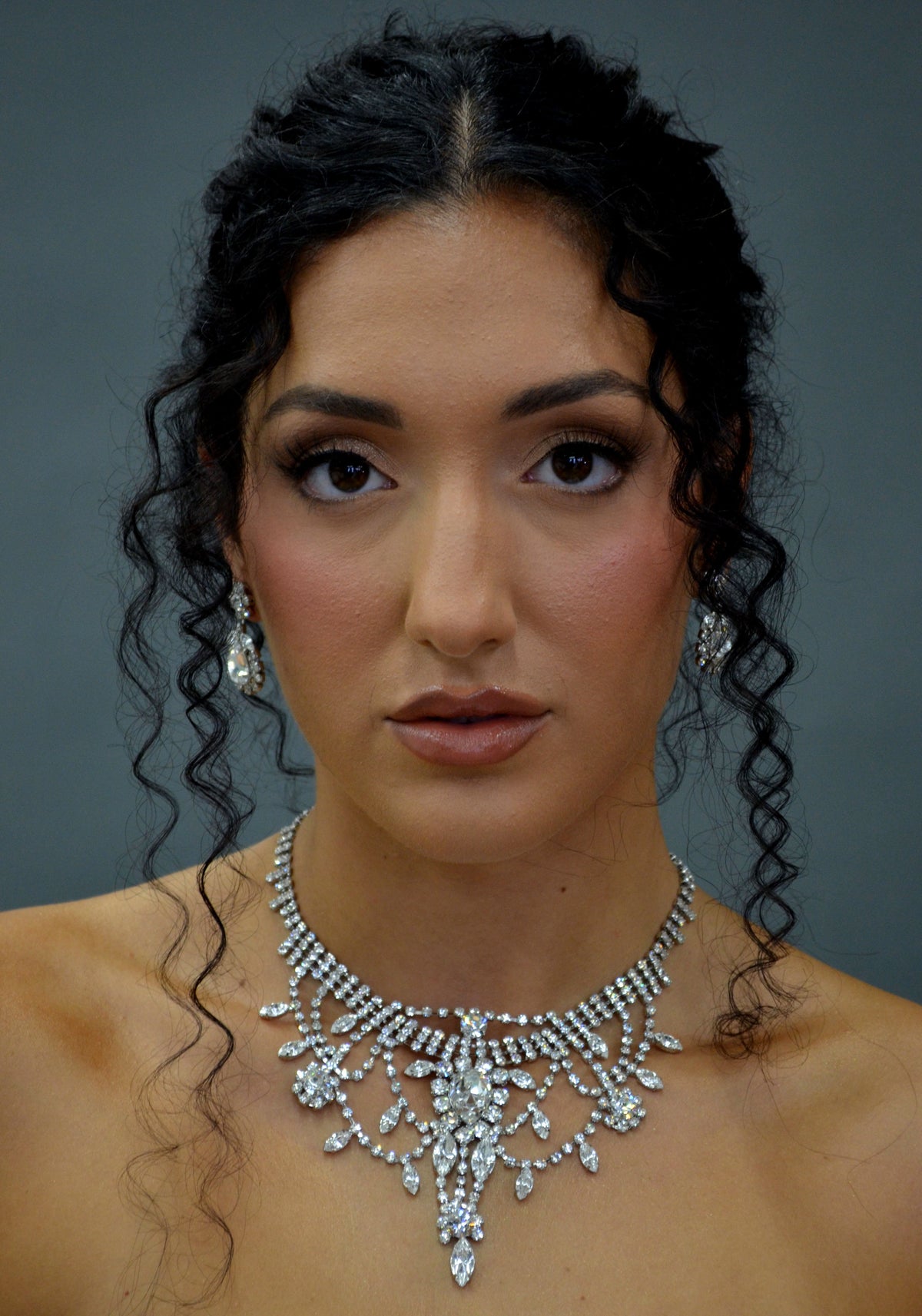 Statement crystal necklace-and-earring set featuring dramatic waterfall silhouette with marquise and teardrop stones,…