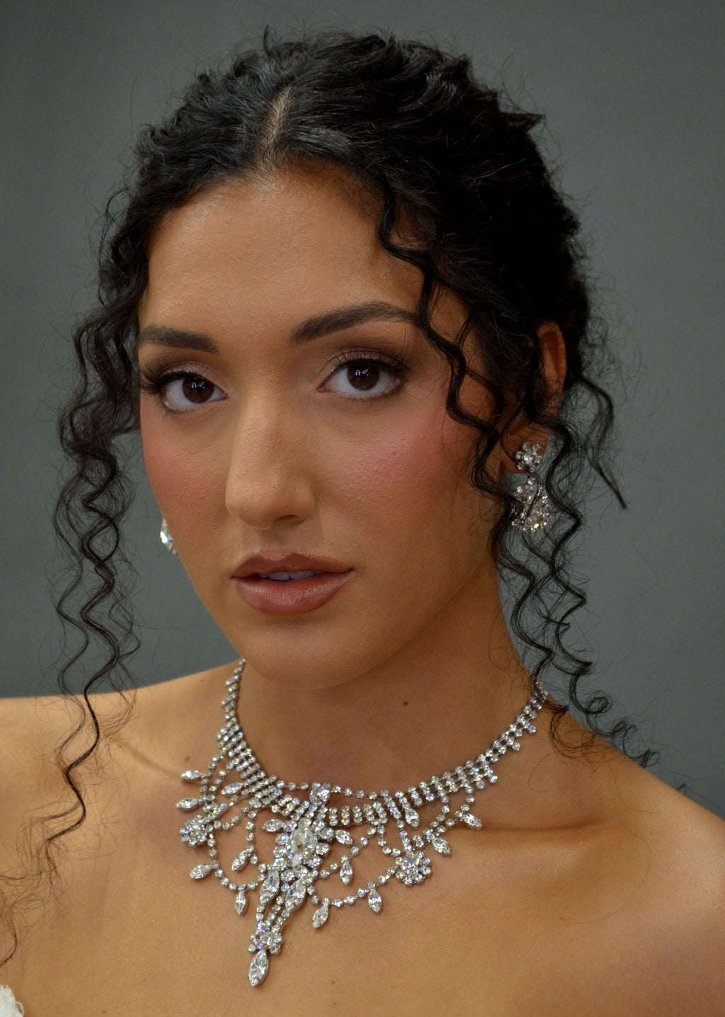Statement crystal necklace-and-earring set featuring dramatic waterfall silhouette with marquise and teardrop stones,…