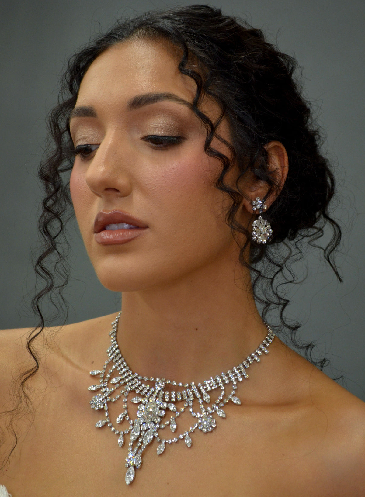 Statement crystal necklace-and-earring set featuring dramatic waterfall silhouette with marquise and teardrop stones,…