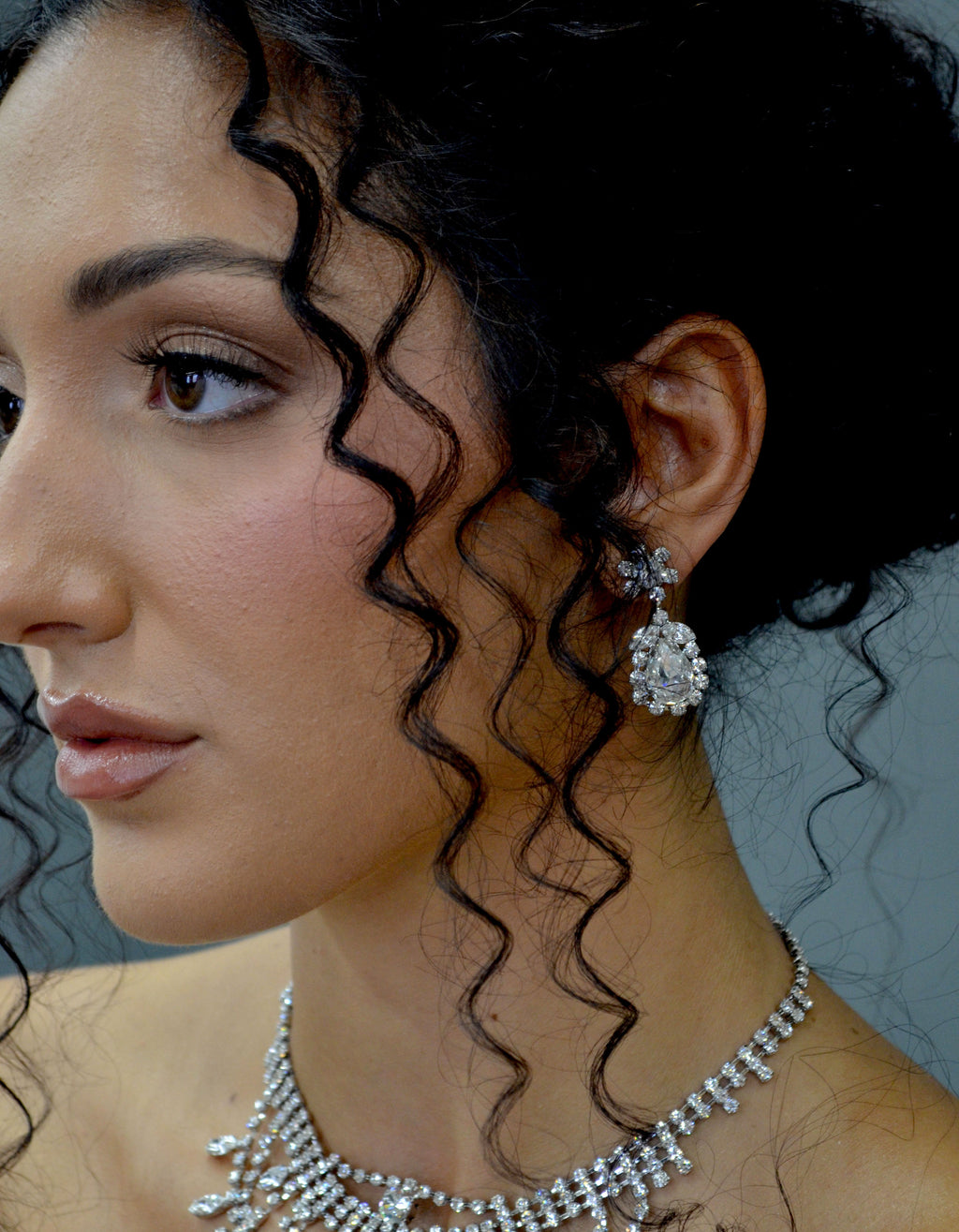 Statement crystal necklace-and-earring set featuring dramatic waterfall silhouette with marquise and teardrop stones, view…