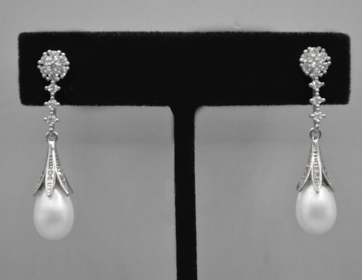 Pear-cut crystal drop earrings featuring faceted teardrop stone beneath a petite geometric crystal top, detail view at…