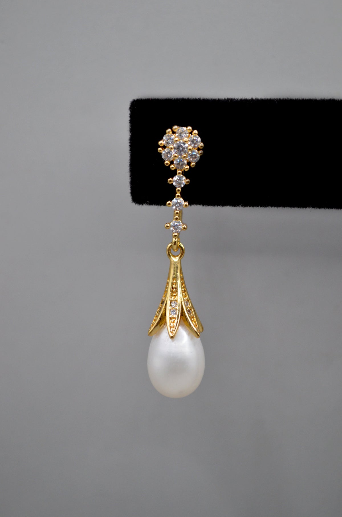 Pear-cut crystal drop earrings featuring faceted teardrop stone beneath a petite geometric crystal top, product view at…