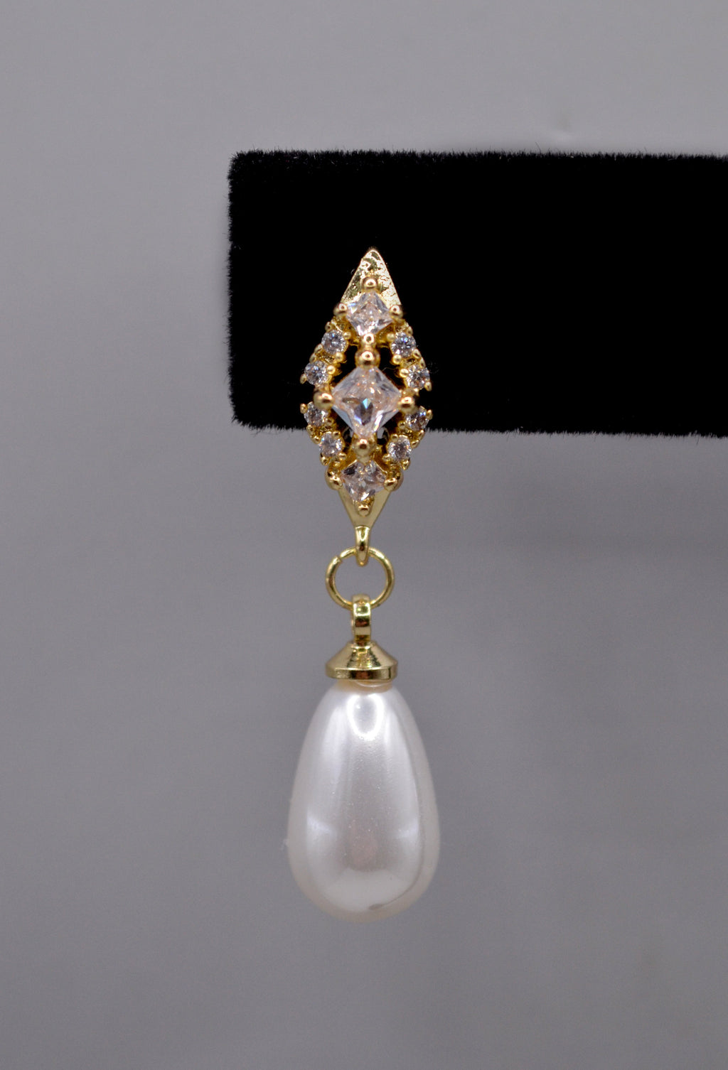 Pearl teardrop earrings featuring luminous pear-shaped pearl suspended from a petite crystal setting, detail view at…