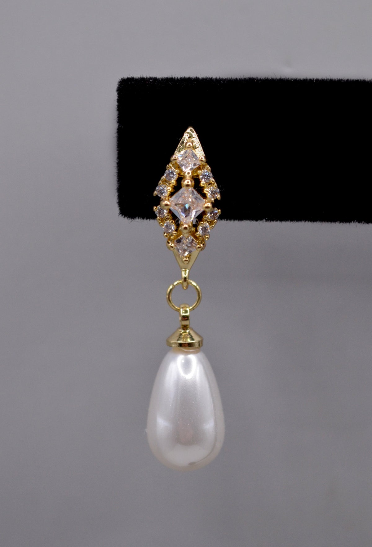 Pearl teardrop earrings featuring luminous pear-shaped pearl suspended from a petite crystal setting, detail view at…