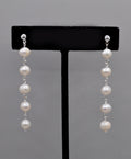 Long pearl strand earrings featuring graduated freshwater-style pearls linked in a graceful linear drop, product view at…