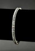 Baguette crystal tennis bracelet featuring continuous line of rectangular stones in a sleek setting, product view at…