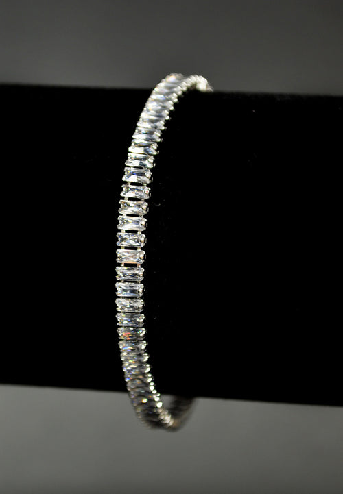 Baguette crystal tennis bracelet featuring continuous line of rectangular stones in a sleek setting, product view at…