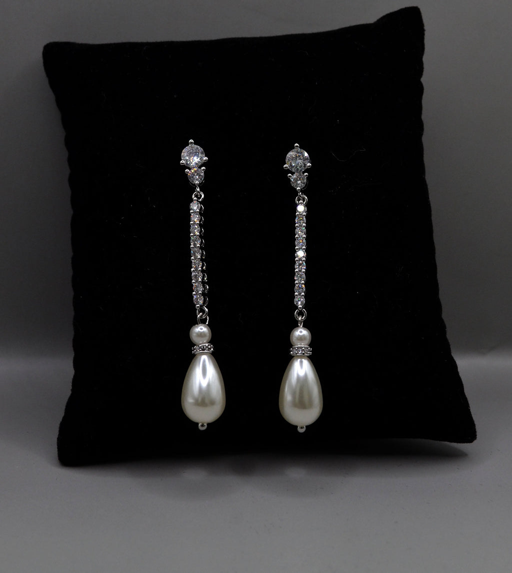 Delicate pearl drop earrings featuring fine linear crystal stem finished with a petite pearl, product view at Rebecca’s…