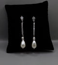 Delicate pearl drop earrings featuring fine linear crystal stem finished with a petite pearl, product view at Rebecca’s…