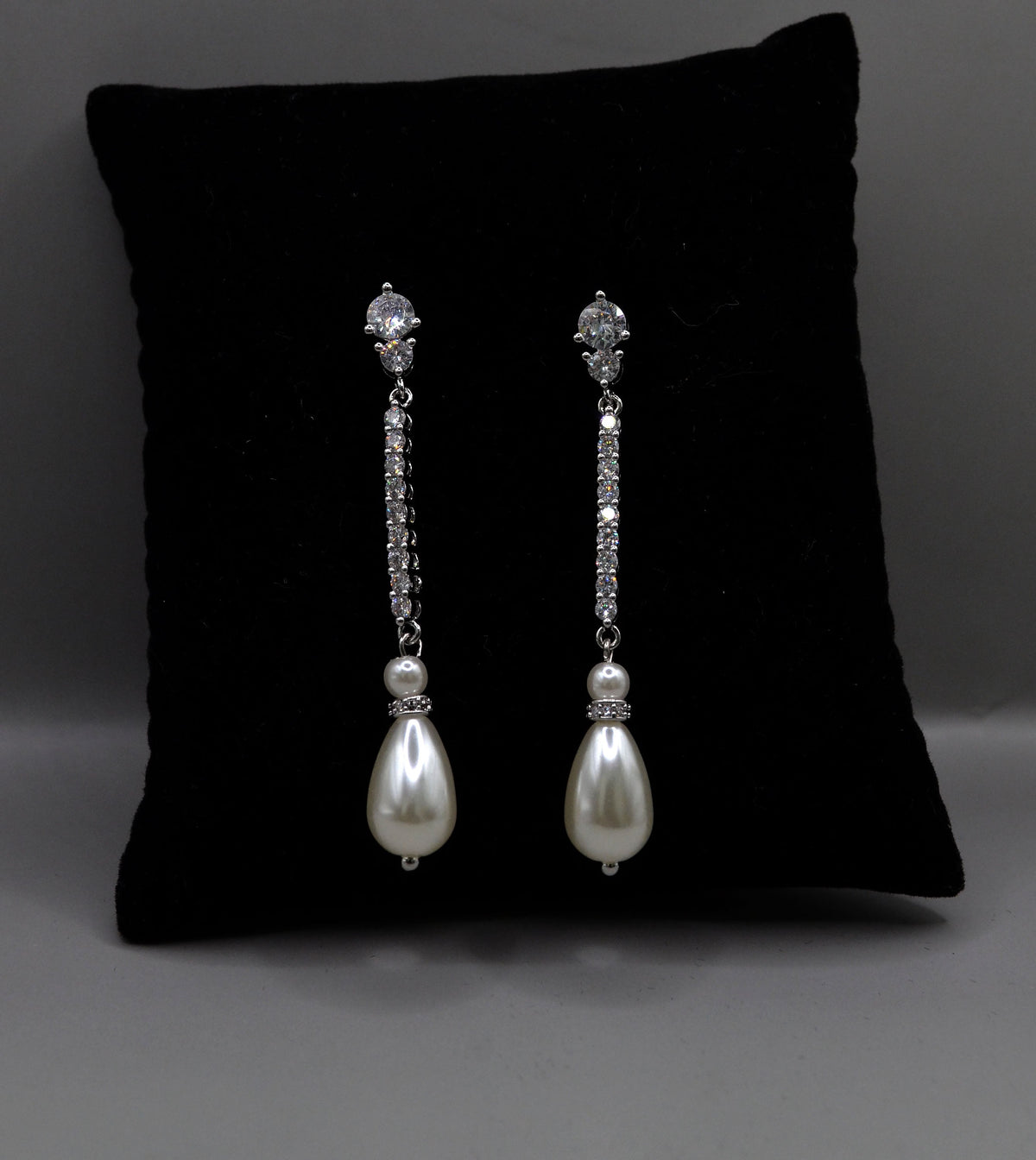 Delicate pearl drop earrings featuring fine linear crystal stem finished with a petite pearl, product view at Rebecca’s…