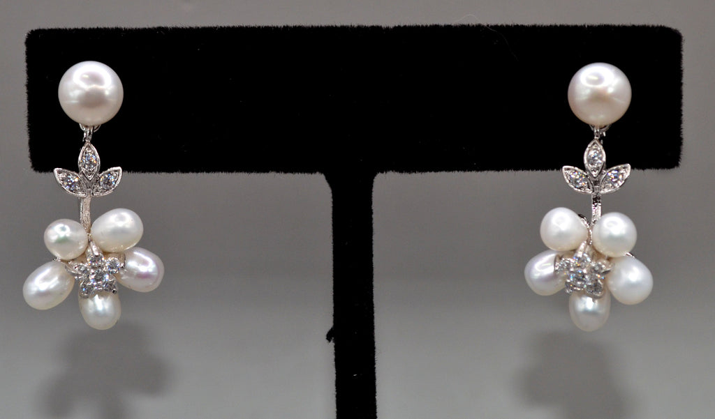 Pearl flower drop earrings featuring pearl stud with a delicate cluster of pearls and crystal leaves, product view at…